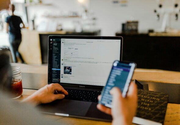 Person using a phone alongside a laptop, representing multi-device connectivity
